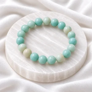 Natural Amazonite Crystal Bracelet with polished aqua-green round gemstone beads displayed on a white circular crystal plate.