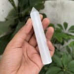 Natural Selenite Crystal Pencil Tower held in hand with white fibrous texture and pointed tip