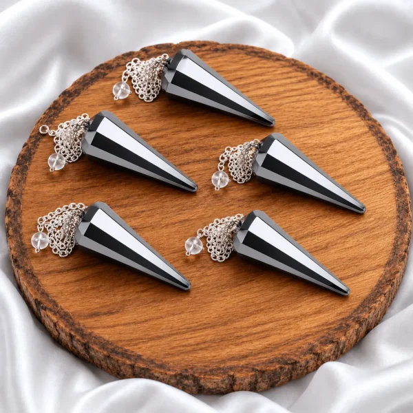 Natural hematite dowser pendulums with silver chains displayed on a wooden crystal stand