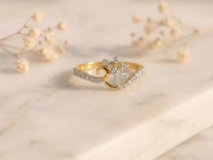 Elegant gold ring featuring a diamond floral motif and a pavé-set waving band on marble.