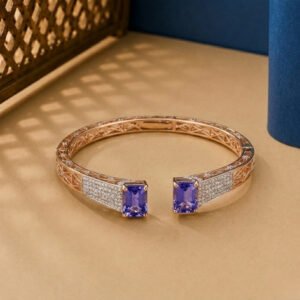 A rose gold ribbed bangle featuring alternating vertical rows of pink stones and white diamonds on a neutral background.