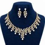Pear cut floral lab grown diamond bridal necklace set with matching leaf design drop earrings displayed on navy blue jewellery bust