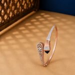 A yellow gold hinged bangle featuring seven graduated oval stations set with pavé diamonds on a neutral background.