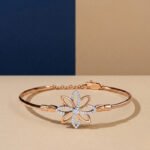 A handcrafted diamond vine bracelet with a blue enamel butterfly and safety chain in yellow gold.