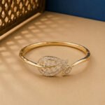 A handcrafted yellow gold diamond vine bracelet with a large pavé-set diamond leaf on a neutral background.