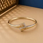 A yellow gold diamond vine bracelet with an oval pavé centerpiece and open-link details on a neutral background.