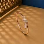 A yellow gold modern abstract diamond vine bracelet featuring a pavé section and a geometric bypass tip on a neutral background.