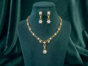 An elegant golden vine necklace and earring set featuring floral diamond clusters on a deep emerald velvet bust.