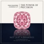 Loose fancy vivid pink cushion cut diamond showing perfect rounded square faceting and brilliant light reflections on a soft white surface.