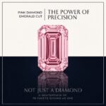 Loose fancy vivid pink emerald cut diamond showing clean step-cut faceting and linear light reflections on a soft white surface.