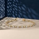 Luminous marquis link lab-grown diamond bracelet shown in a yellow-toned metal on a textured neutral surface.