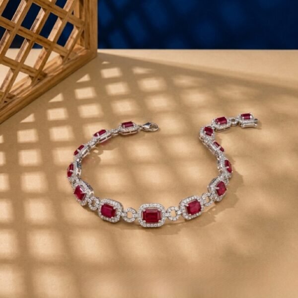 Emerald-cut lab ruby and diamond halo bracelet in white metal.
