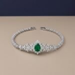 Pear-cut lab emerald statement bracelet with marquise diamond floral clusters in white metal.