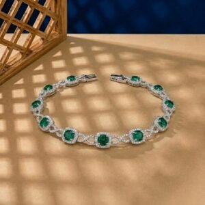 Cushion-cut lab emerald infinity bracelet with diamond halos in white metal.