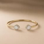 Pear-cut lab diamond open cuff bangle with diamond halos in yellow gold.