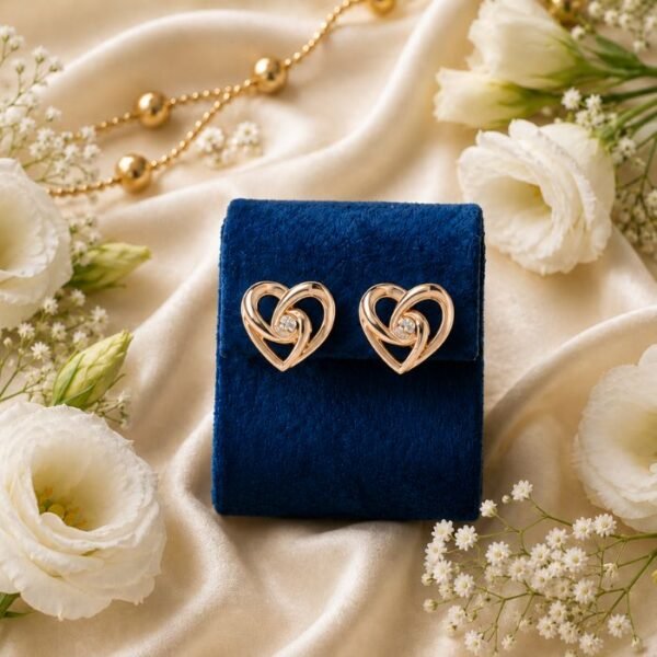Pair of intertwined rose gold lab-grown diamond heart stud earrings displayed on a blue velvet stand.