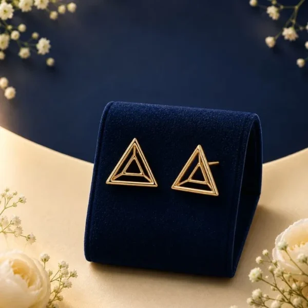 Pair of 18K yellow gold 3D geometric stud earrings featuring a concentric open triangle design, displayed on a royal blue velvet jewelry stand.