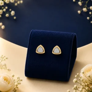 A pair of 18K yellow gold rounded trillion shield-shaped stud earrings featuring a pave cluster of lab-grown diamonds, displayed on a royal blue velvet mount.