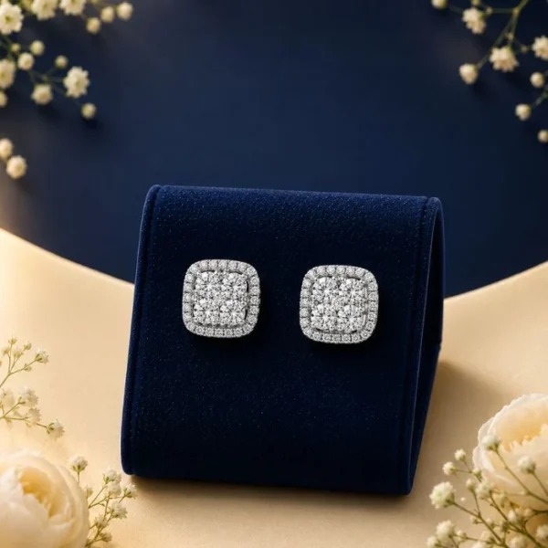 A pair of 18K white gold cushion-shaped halo stud earrings featuring a composite cluster of lab-grown diamonds, displayed on a blue velvet mount.