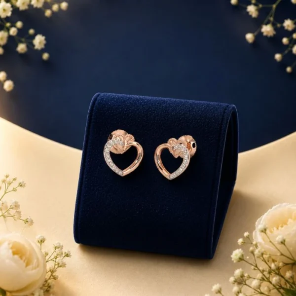 Pair of 18K rose gold interlocking open-heart stud earrings featuring a pave row of white lab-grown diamonds on the upper loop, displayed on a navy blue velvet mount.