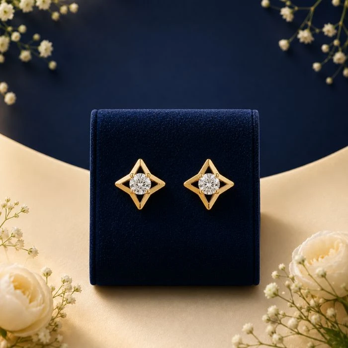 Lyra Elongated Tear-Drop Diamond Earrings Pair of 18K yellow gold elongated tear-drop loop earrings featuring a three-stone trinity cluster of white lab-grown diamonds, displayed on a blue velvet mount.