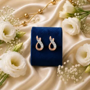 Rose gold infinity lab grown diamond huggie earrings on blue velvet box