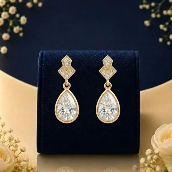 Lab grown diamond pear drop earrings in gold with pear shaped diamonds on navy velvet jewellery display