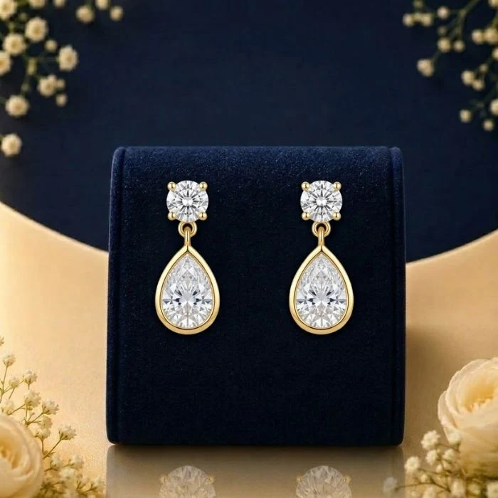 Pear Halo Lab Grown Diamond Drop Earrings Lab grown diamond pear drop earrings with round solitaire tops on navy velvet jewellery display