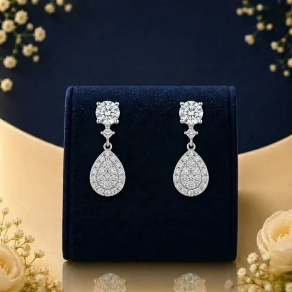 Lab grown diamond pear drop earrings with round solitaire tops on navy velvet jewellery display