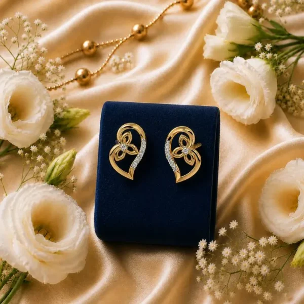 14k gold heart diamond studs with a floral motif design inside, displayed on a dark blue velvet box with white flowers.