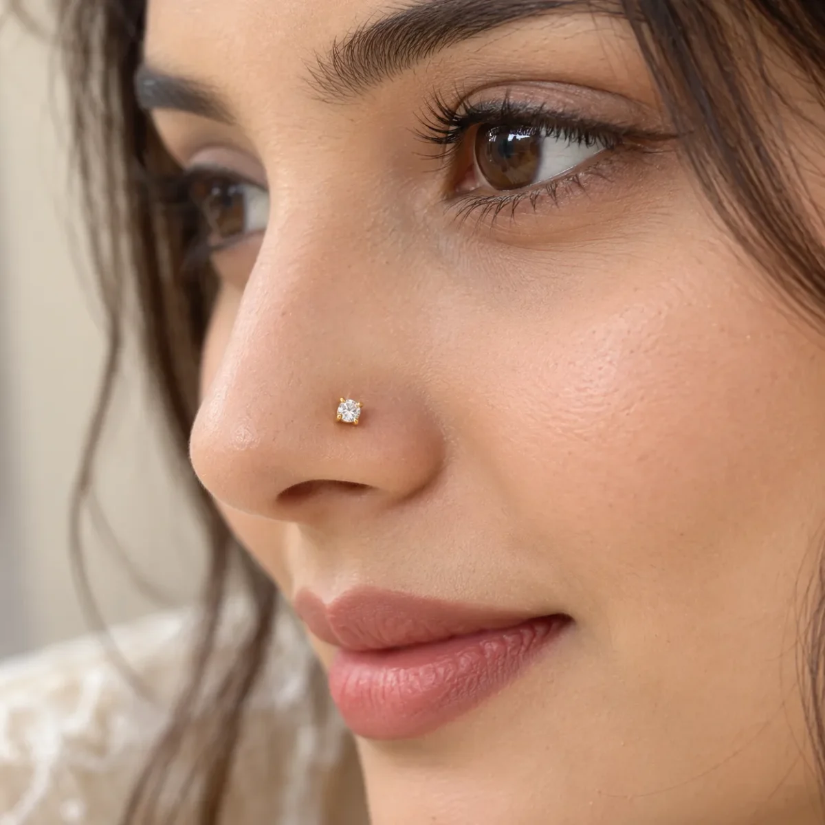 Model wearing a small Lumi Solitaire Lab Grown Diamond Nose Pin in yellow gold with a round diamond.
