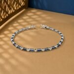 Vintage-style bracelet featuring baguette-cut blue sapphires and round lab diamonds with milgrain edges on a tan and blue background.