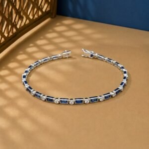 Vintage-style bracelet featuring baguette-cut blue sapphires and round lab diamonds with milgrain edges on a tan and blue background.