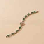 Emerald and Lab Diamond Bracelet featuring alternating green emeralds and round diamonds with a center clover motif.