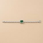 Emerald Halo Lab Diamond Bracelet featuring a green emerald-cut center stone with a diamond halo on a tan background.