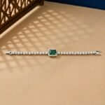 Emerald Halo Lab Diamond Bracelet featuring a green emerald-cut center stone with a diamond halo on a tan background