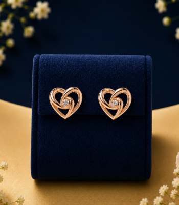 Pair of intertwined rose gold lab-grown diamond heart stud earrings displayed on a blue velvet stand.