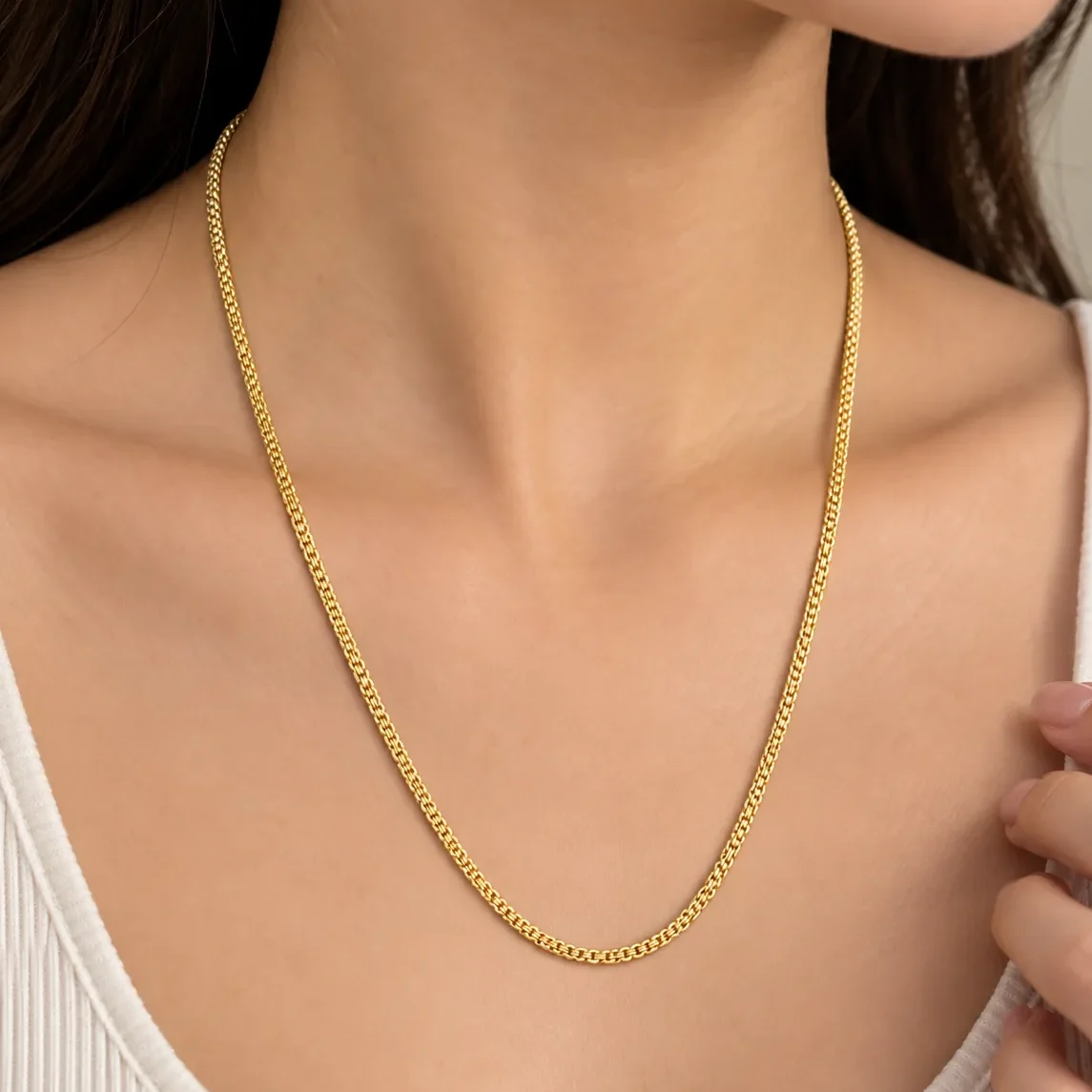 Woman wearing an elegant 18K yellow gold chain with a refined woven-style link design