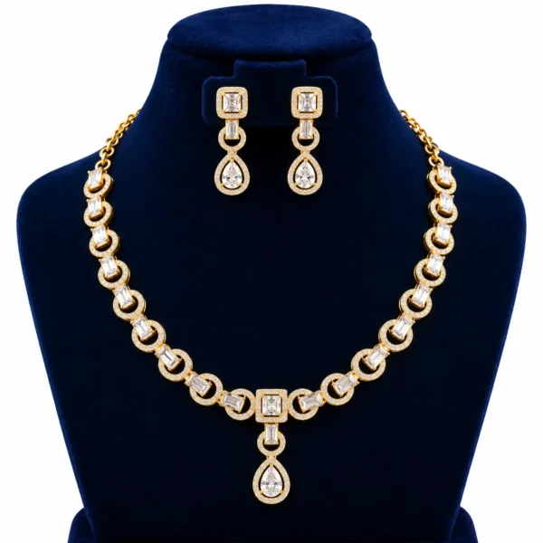 18K Gold Baguette Cut Lab Grown Diamond Halo Necklace Set with Matching Earrings featuring sparkling rectangular baguette diamonds, circular diamond halo links, square diamond centrepiece and elegant pear-shaped drop pendant on a navy blue jewellery display.