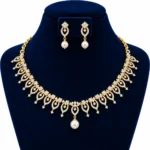 18K gold floral leaf lab grown diamond necklace set with central white pearl drop and matching pearl earrings displayed on navy blue jewellery bust