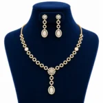 18K Gold Floral Oval Lab Grown Diamond Necklace Set with Matching Earrings featuring circular diamond motifs, floral centre pendant and elegant oval drop design displayed on a navy blue jewellery stand.