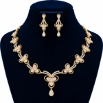 18K gold lab grown diamond floral necklace set with three-petal diamond flowers, central teardrop pendant and matching drop earrings on navy blue jewellery bust