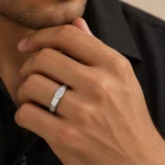 Regal Emerald Moissanite Men's Ring in silver worn on a male model's finger, featuring an emerald-cut Moissanite stone.